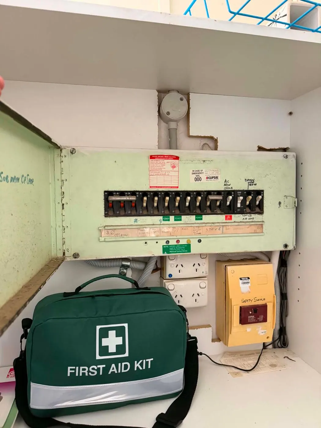 Older commercial switchboard with a single safety switch added later in a separate yellow enclosure below the board