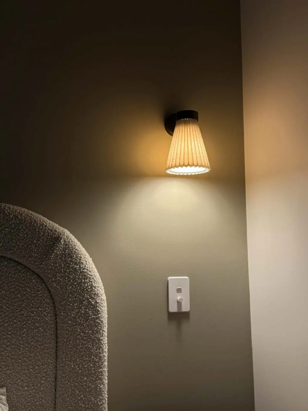 Dimmable wall sconce beside a bedhead in a Redwood Park master suite, with the dimmer switch below